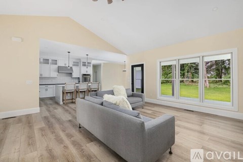 A living room with a grey couch and a kitchen in the background.