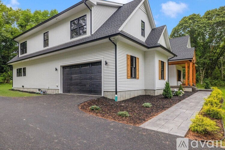 A modern house with a grey garage door and a black roof.