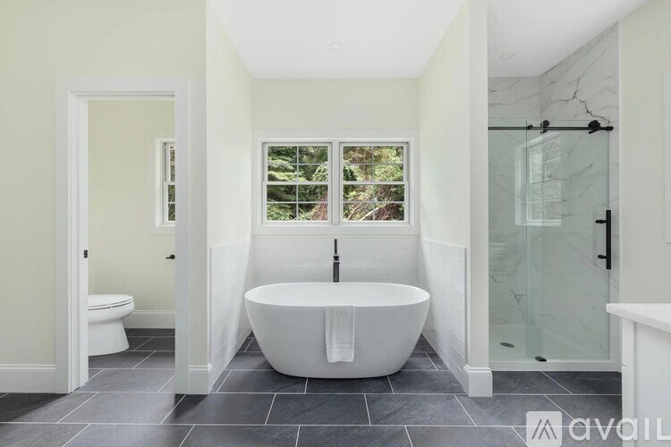 A bathroom with a white tub and a window.