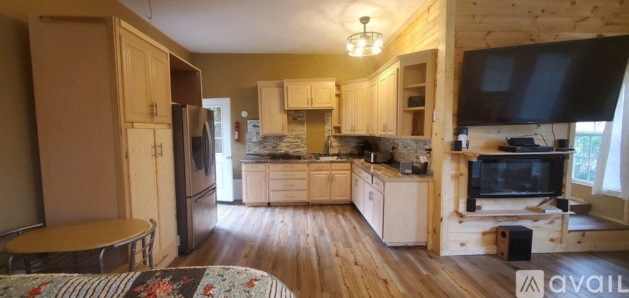 A kitchen with wooden floors and a black television mounted above the stove.