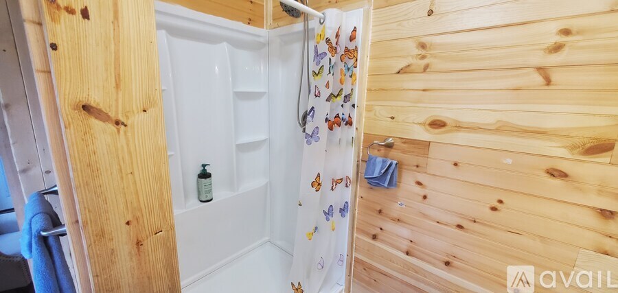A wooden bathroom with a shower curtain and a towel hanging on the wall.