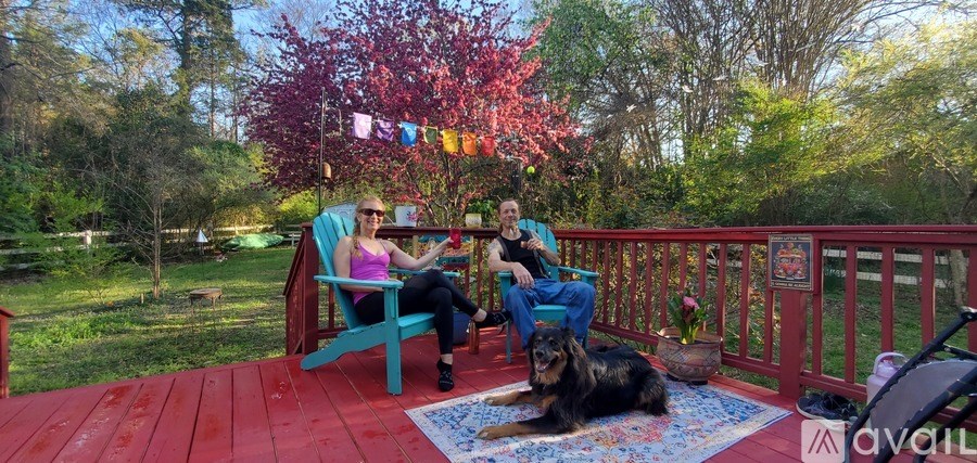 Two people sitting on a porch with a dog.