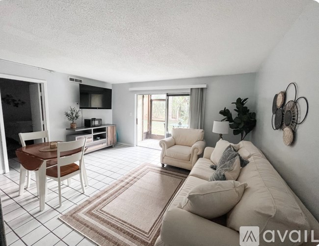 A living room with a couch, chairs, and a dining table.