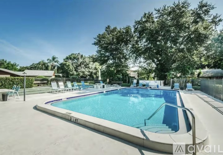 A swimming pool surrounded by trees and chairs.