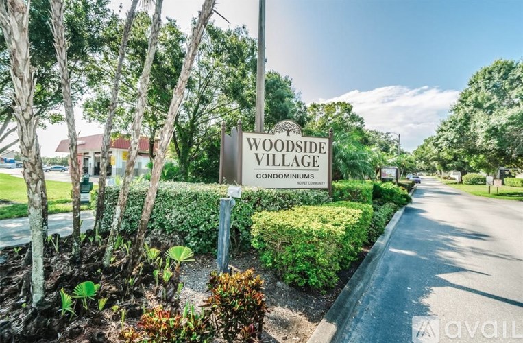 A sign for Woodside Village Condominiums is surrounded by greenery.