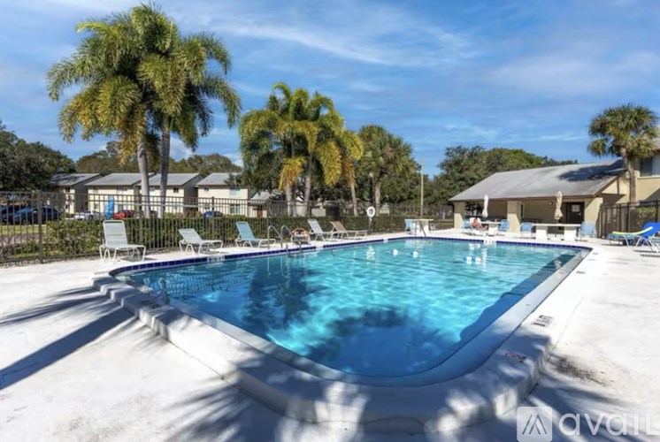 A large outdoor swimming pool surrounded by palm trees and lounge chairs.