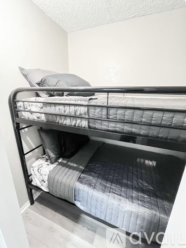 A bunk bed with a grey blanket and pillow is in a room.
