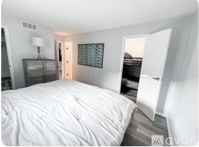 A bedroom with a large bed and a dresser with a lamp on it.