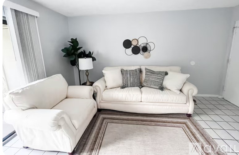 A living room with a white couch and a white chair.
