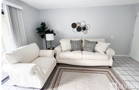 A living room with a white couch and a white chair.
