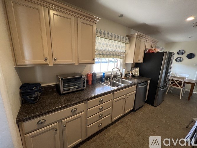 A kitchen with wooden cabinets and a black refrigerator.