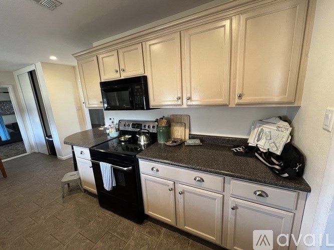 A kitchen with black appliances and white cabinets.