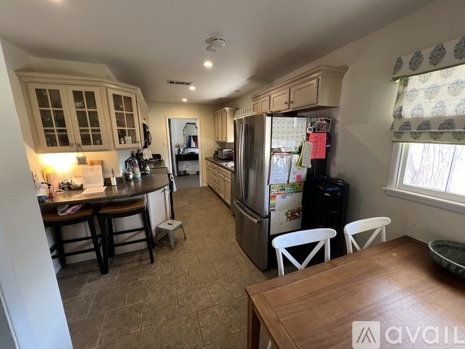 A kitchen with a refrigerator, table, and chairs.