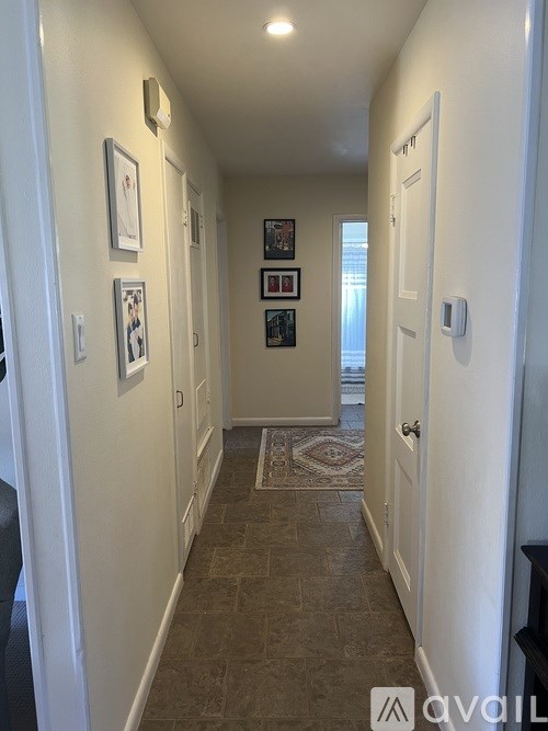 A hallway with a rug and pictures on the wall.