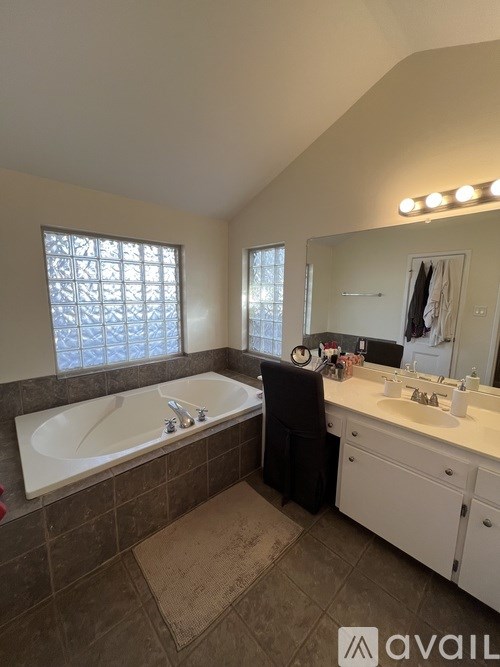 A bathroom with a tub, sink, and mirror.