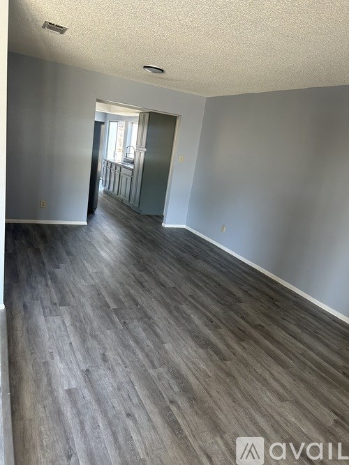 A room with wooden flooring and a doorway leading to another room.
