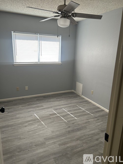 A room with a ceiling fan and a window with blinds.