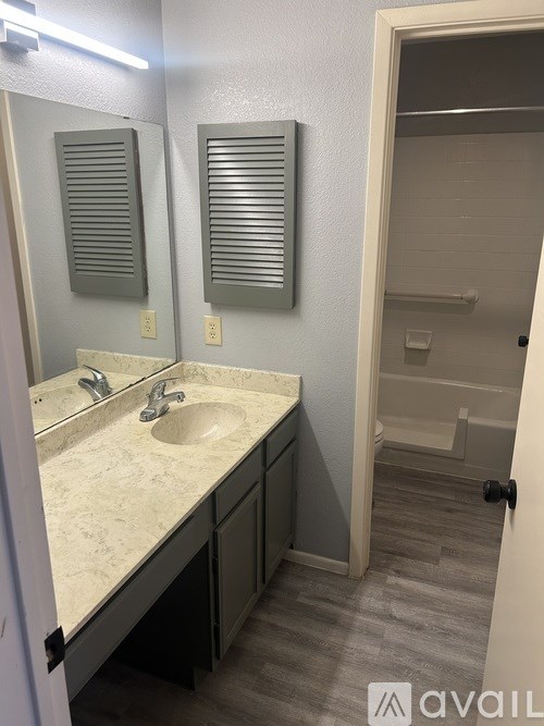 A bathroom with a sink, mirror, and a door.