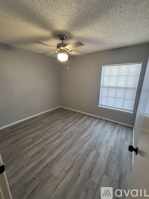A room with a ceiling fan and a window with blinds.