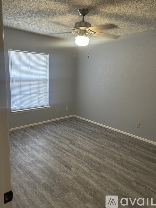 A room with a ceiling fan and a window with blinds.