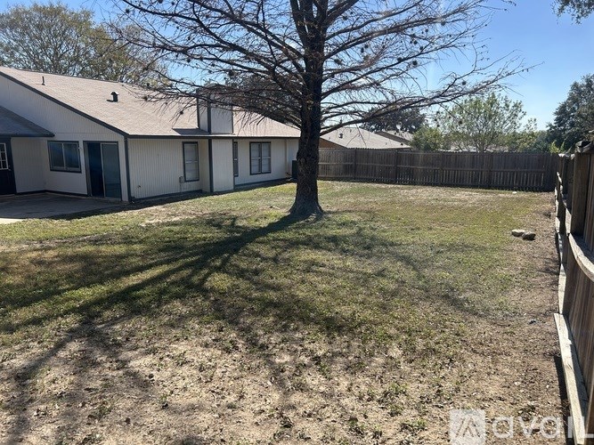 A tree in a yard with a house in the background.