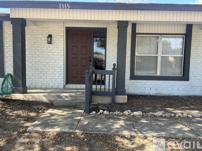 A white house with a red door and a black railing.