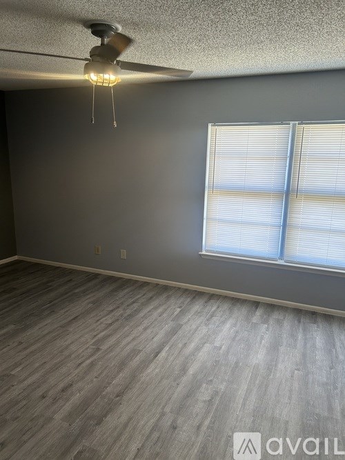 A room with a ceiling fan and a window with blinds.