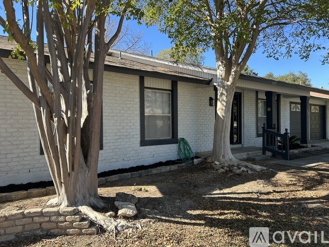 A white house with a tree in front of it.