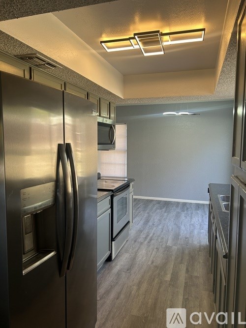 A kitchen with a stainless steel refrigerator and wooden flooring.