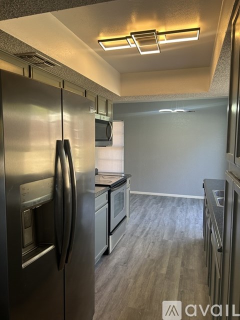 A kitchen with a stainless steel refrigerator and wooden flooring.