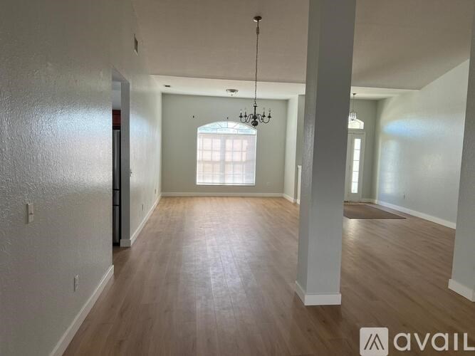 A spacious room with wooden floors and a chandelier hanging from the ceiling.
