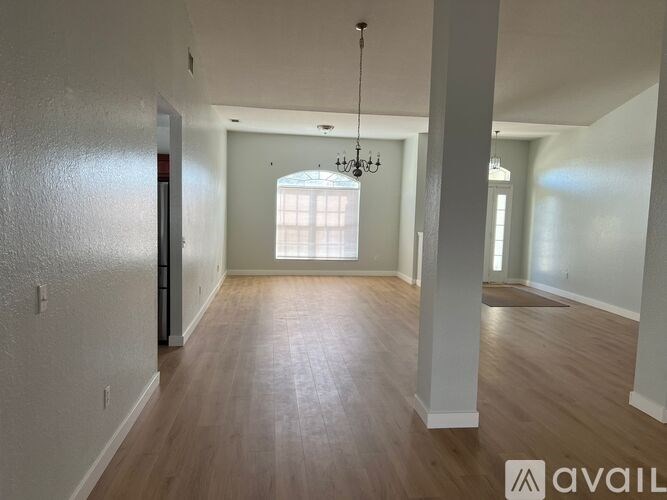A spacious room with wooden floors and a chandelier hanging from the ceiling.