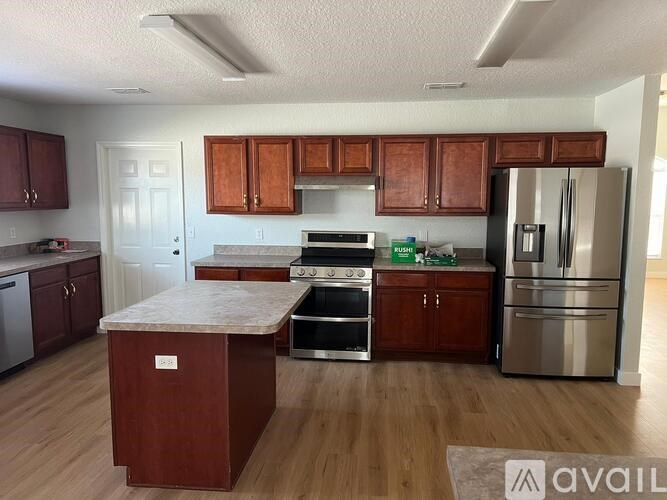 A kitchen with wooden cabinets and stainless steel appliances is available for rent.