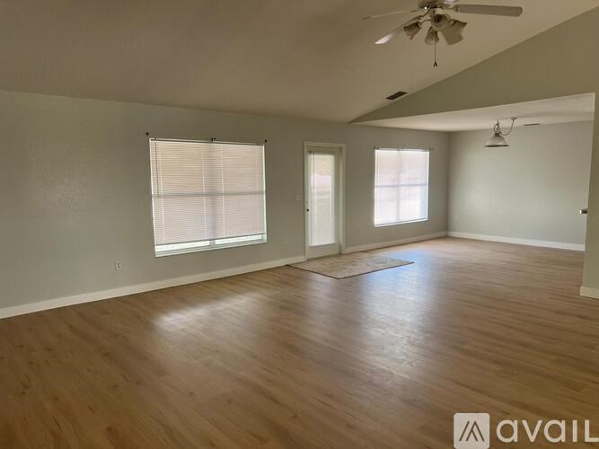A spacious room with wooden floors and a ceiling fan.