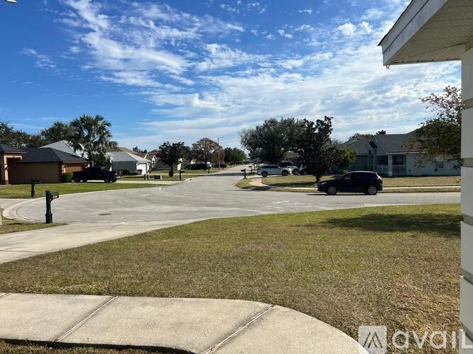 A residential street with houses on both sides and cars parked on the side of the road.