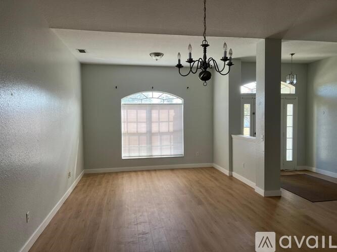 A room with wooden floors and a chandelier hanging from the ceiling.
