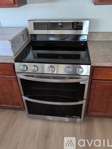 A modern stainless steel oven with a digital display and four burners is installed in a kitchen.