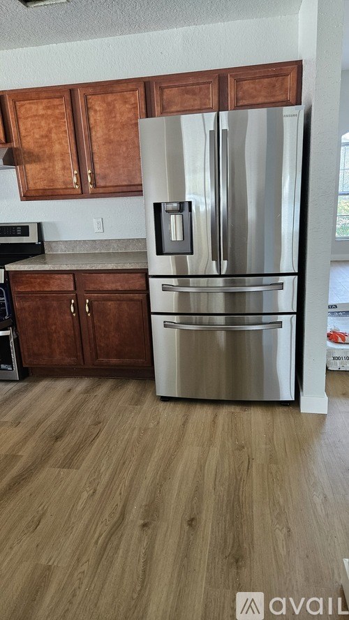 A kitchen with a stainless steel refrigerator and wooden cabinets.