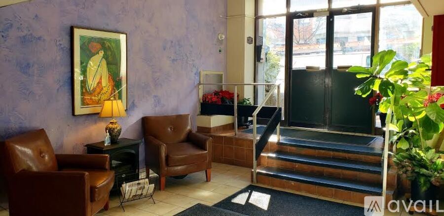 A purple wall with a painting and two chairs.