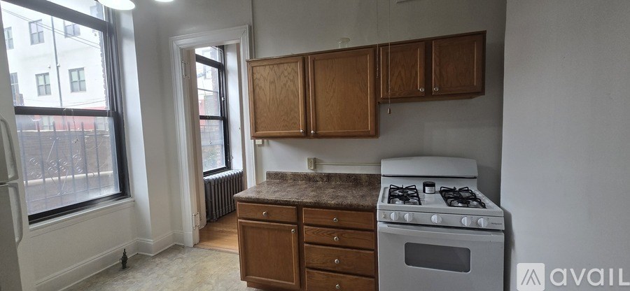 A kitchen with a stove, cabinets, and a window.