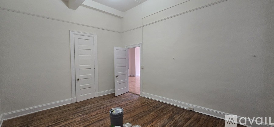 A room with wooden floors and two doors, one of which is open.