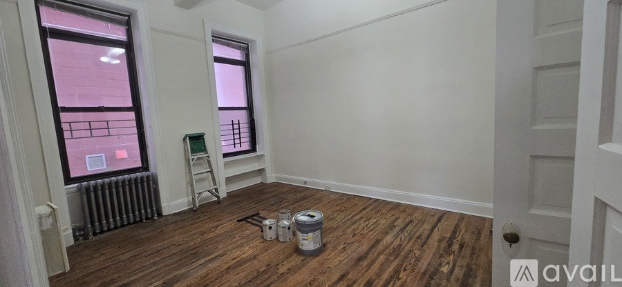 A room with wooden floors and white walls is available for rent.