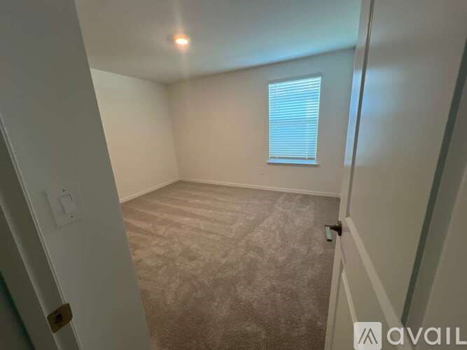 A room with a carpeted floor and a window with blinds.