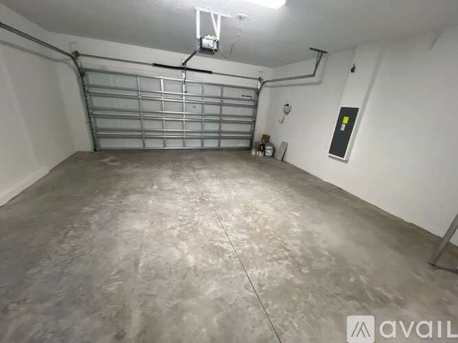 A spacious garage with a concrete floor and a metal rolling shutter door.