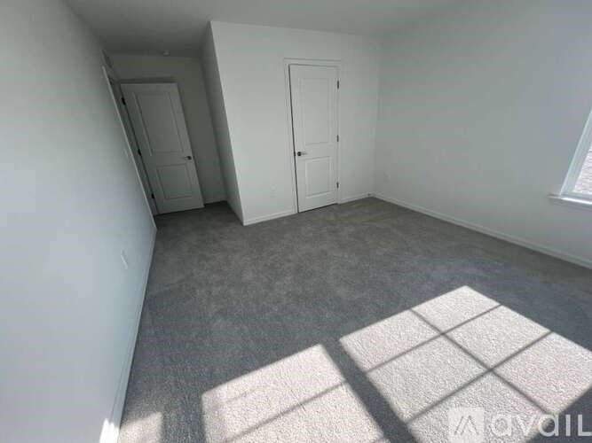 A room with white walls and a grey carpet.