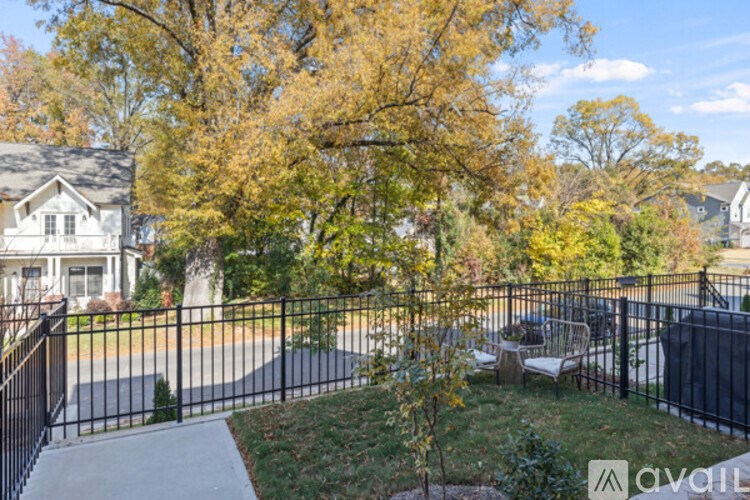 A house with a black fence and a tree with yellow leaves.