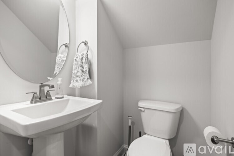 A bathroom with a toilet, sink, and mirror.