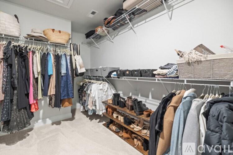 A room with a white wall and a clothing rack with clothes hanging on it.