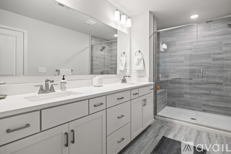 A bathroom with a sink, mirror, and shower.