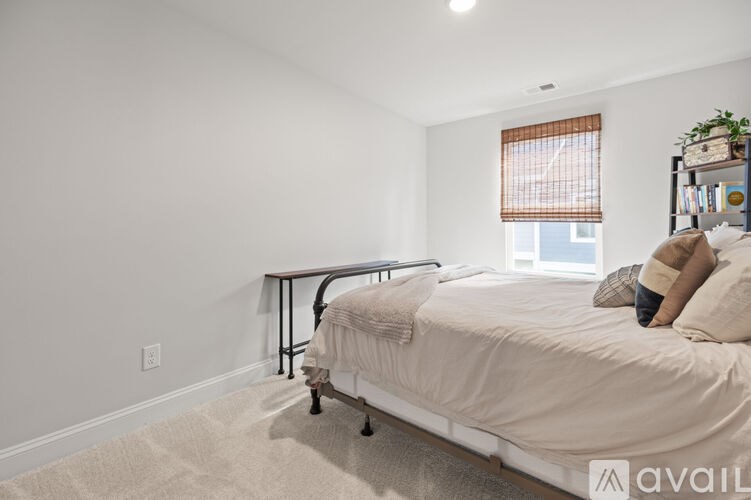 A bedroom with a bed, a small table, and a window with blinds.